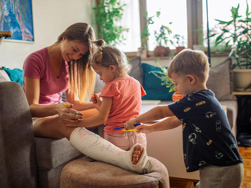 Mutter mit eingegipstem Bein verbringt Urlaub nach Reisestorno mit ihren Kindern zuhause.